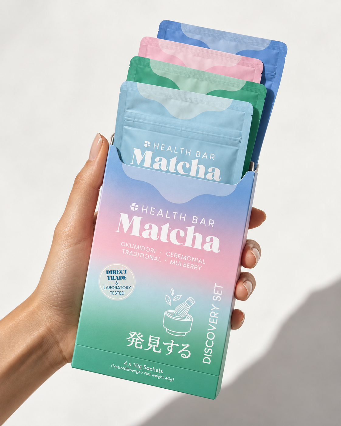 Hand hält das Health Bar Bio Matcha Discovery Set mit vier 10-g-Beuteln