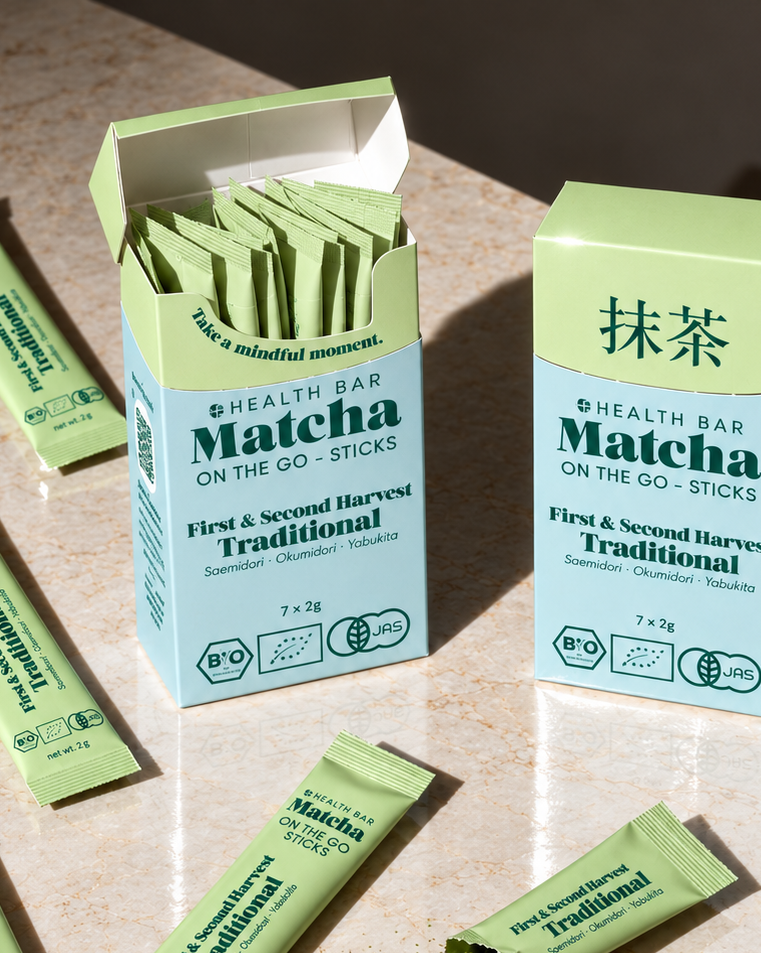 Geöffnete Box Bio Traditional Matcha Sticks von Health Bar, daneben ein offener Stick mit Matcha Pulver