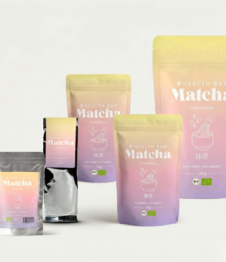 Bio Matcha Pulver Ceremonial von Health Bar im silbernen, luftdichten Beutel mit pastellfarbenem rosa lila Etikett und Hinweis vor hellem Hintergrund
