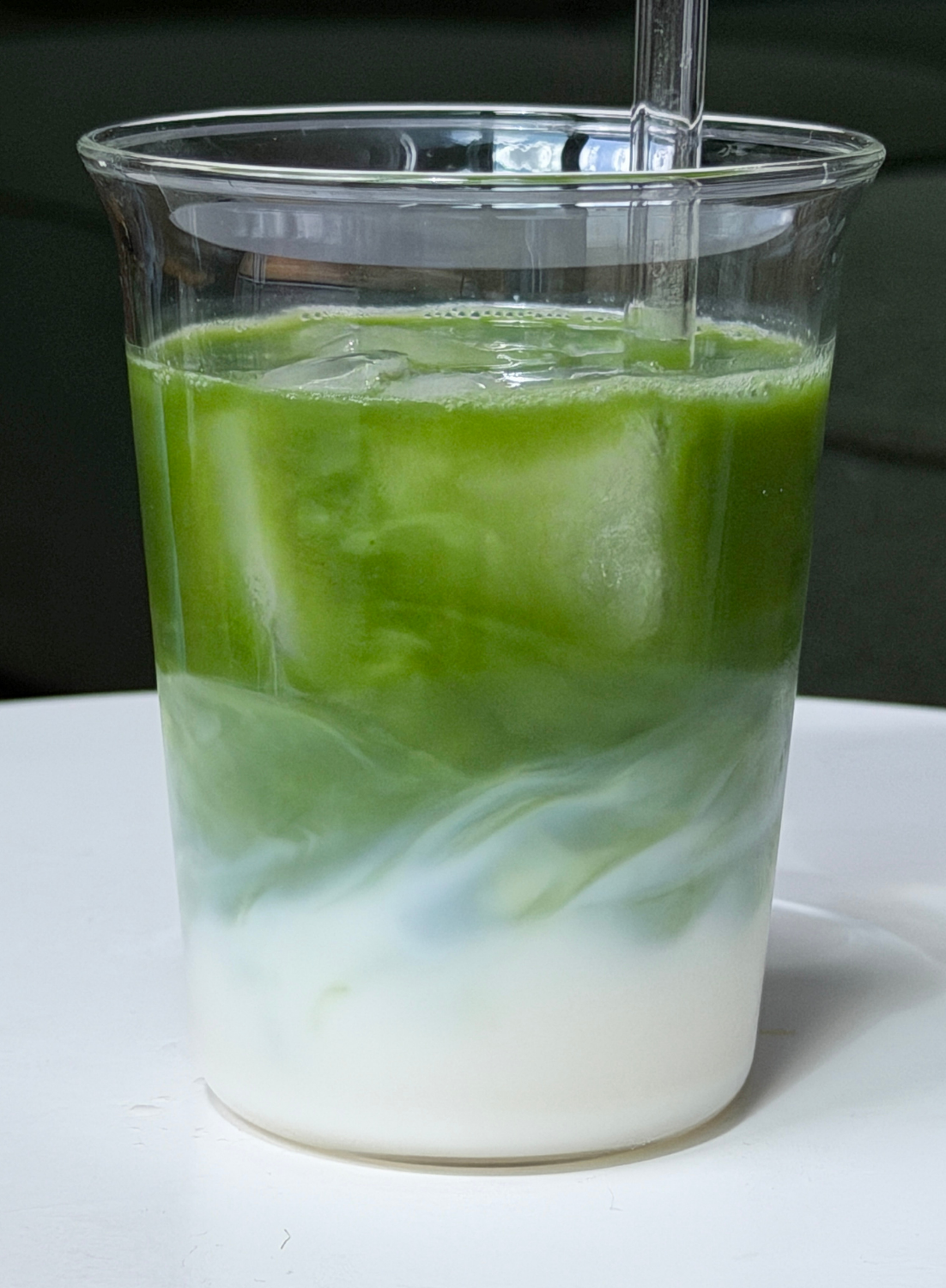 ced Mulberry Matcha Latte im Glas mit Strohhalm – koffeinfreier Mulberry Matcha von Health Bar mit pflanzlicher Milch, sanft-grüner Farbverlauf über Eiswürfeln
