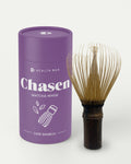 Health Bar Chasen Matcha Whisk aus dunklem Bambus neben lilafarbener Dose mit Aufdruck Chasen Matcha Whisk Dark Bamboo auf hellem Hintergrund