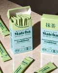 Geöffnete Box Bio Traditional Matcha Sticks von Health Bar, daneben ein offener Stick mit Matcha Pulver