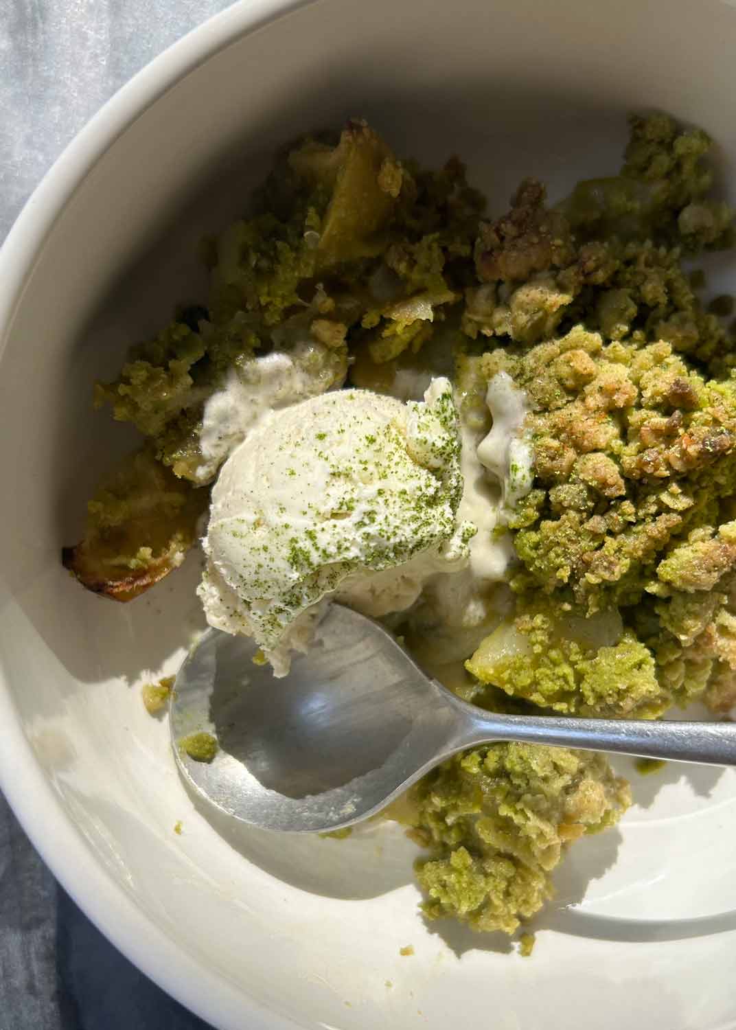 Matcha Apfel Crumble mit geschmolzenem Vanilleeis und Löffel