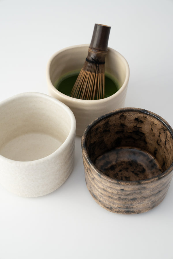 Drei handgemachte Matcha Schalen aus Keramik, eine gefüllt mit cremigem Bio Matcha und Bambus Chasen für das authentische japanische Matcha Ritual
