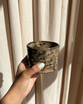 Handgefertigte Chawan Matcha Schale in Cocoa Haze Braun aus Keramik in der Hand gehalten vor hellem Vorhang